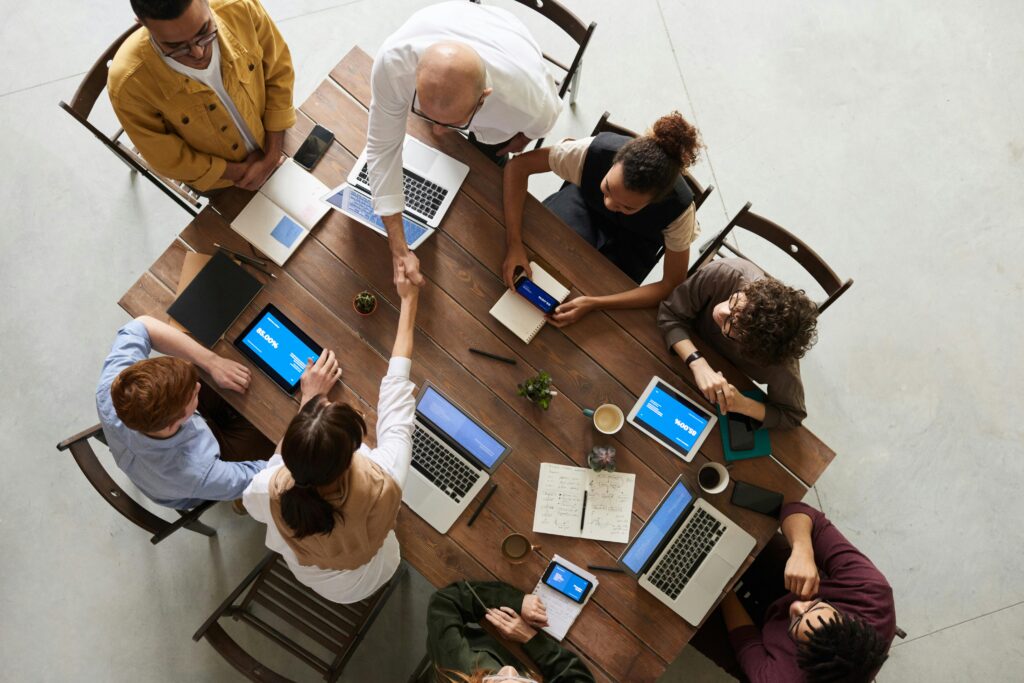 Pentingnya Website Profesional untuk Membangun Kepercayaan Pelanggan Top view of a diverse team collaborating in an office setting with laptops and tablets, promoting cooperation.